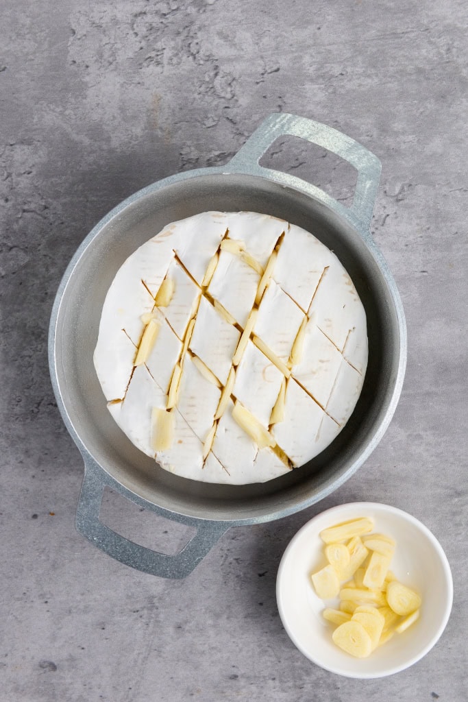 slices of garlic tucked into the slits of the brie wheel