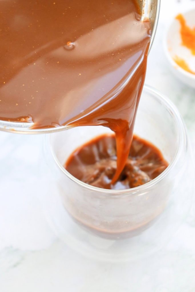 pouring pumpkin spice hot chocolate into glass