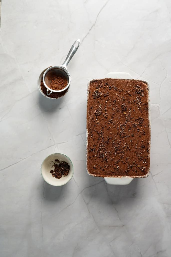 assembled tiramisu garnished with cocoa powder and shaved chocolate