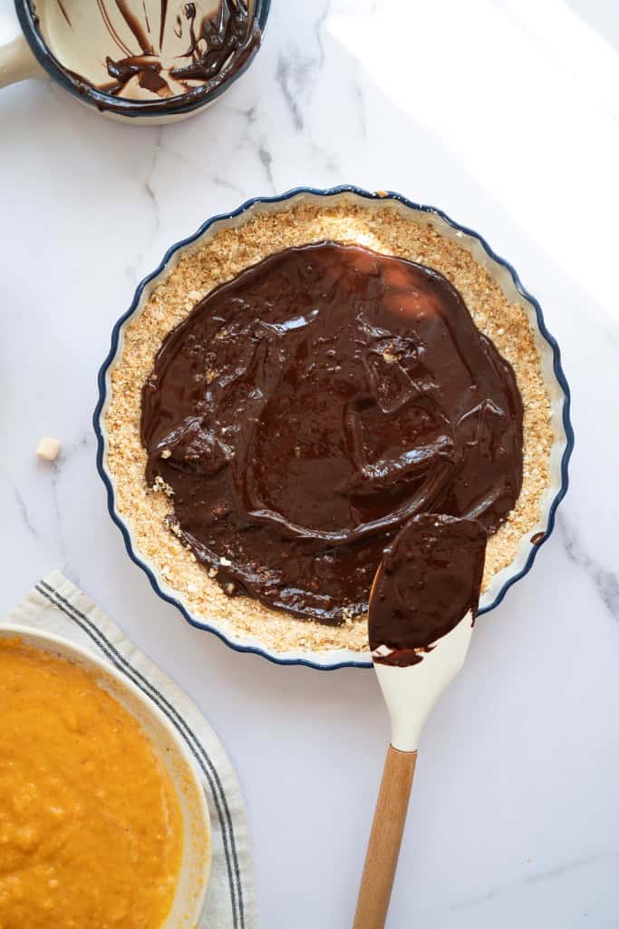 pouring in the chocolate layer into the crust