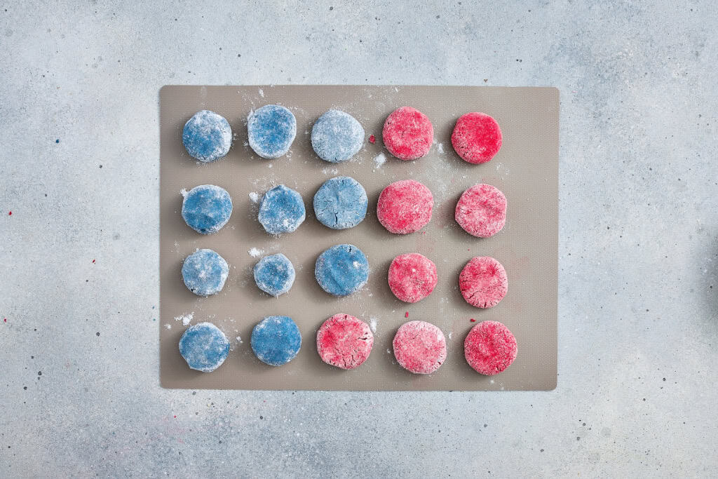 Cookie dough shaped into balls and flattened in a cookie sheet